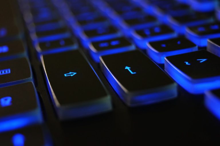 A dark colored keyboard illuminated with blue lighting